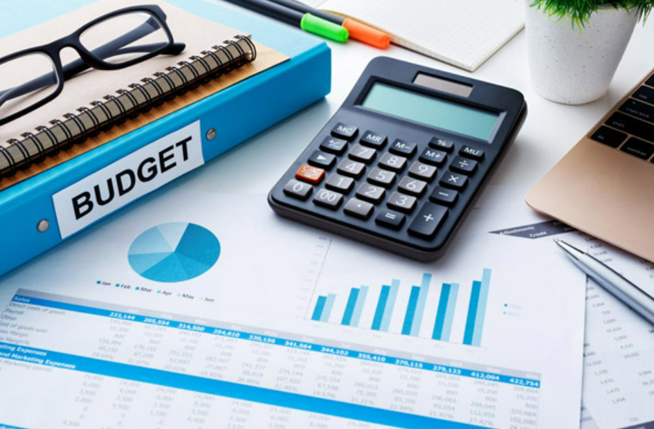 calculator and papers with pie and bar charts to calculate budget